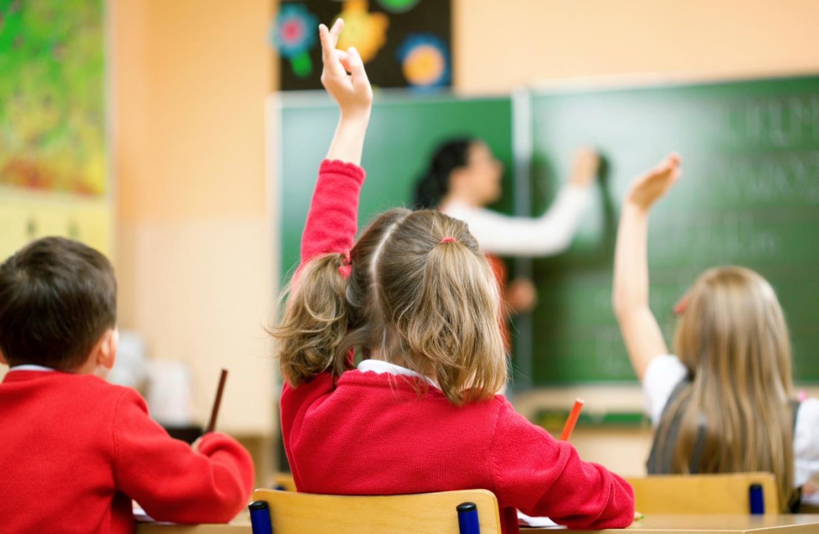 Pupil raising her hand in a classroom.