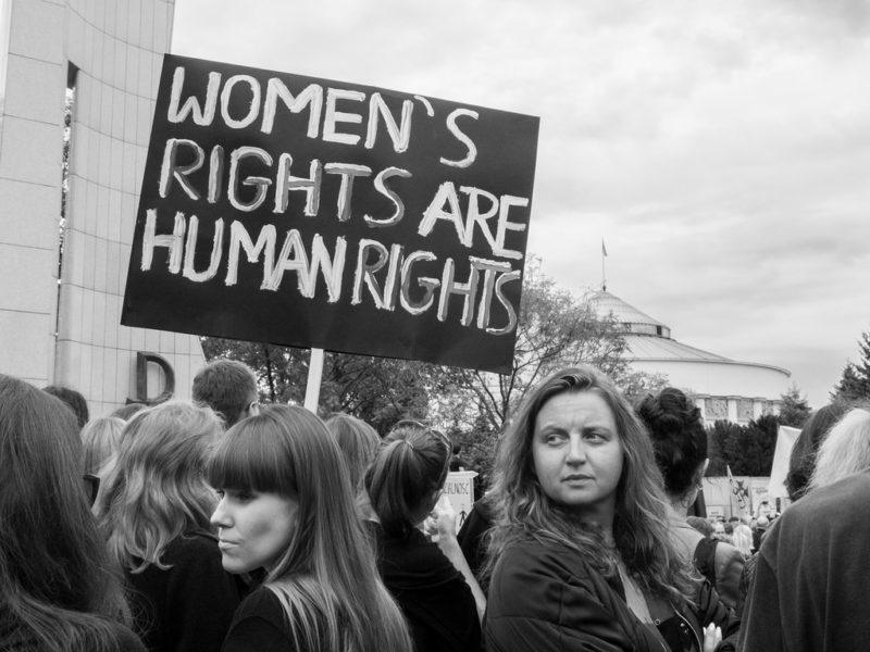 Black and white photo of women holding a sign reading 