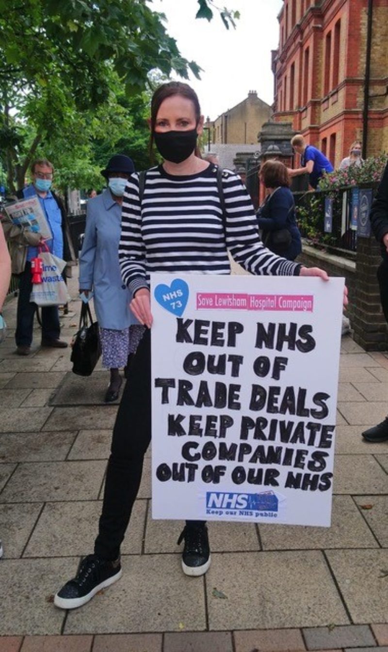 Photo of Vicky with a placard which says "Keep NHS Out Of Trade Deals, Keep Private Companies Out Of Our NHS"