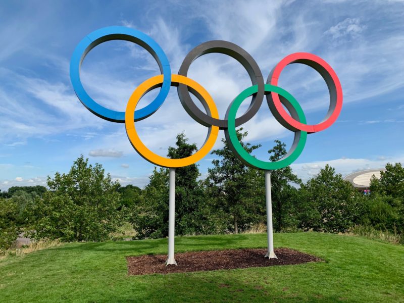 Interlocked statue erected in grass of Olympic rings against a background of a blue sky