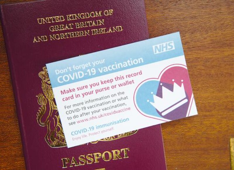 Image of UK Passport underneath COVID Vaccination card