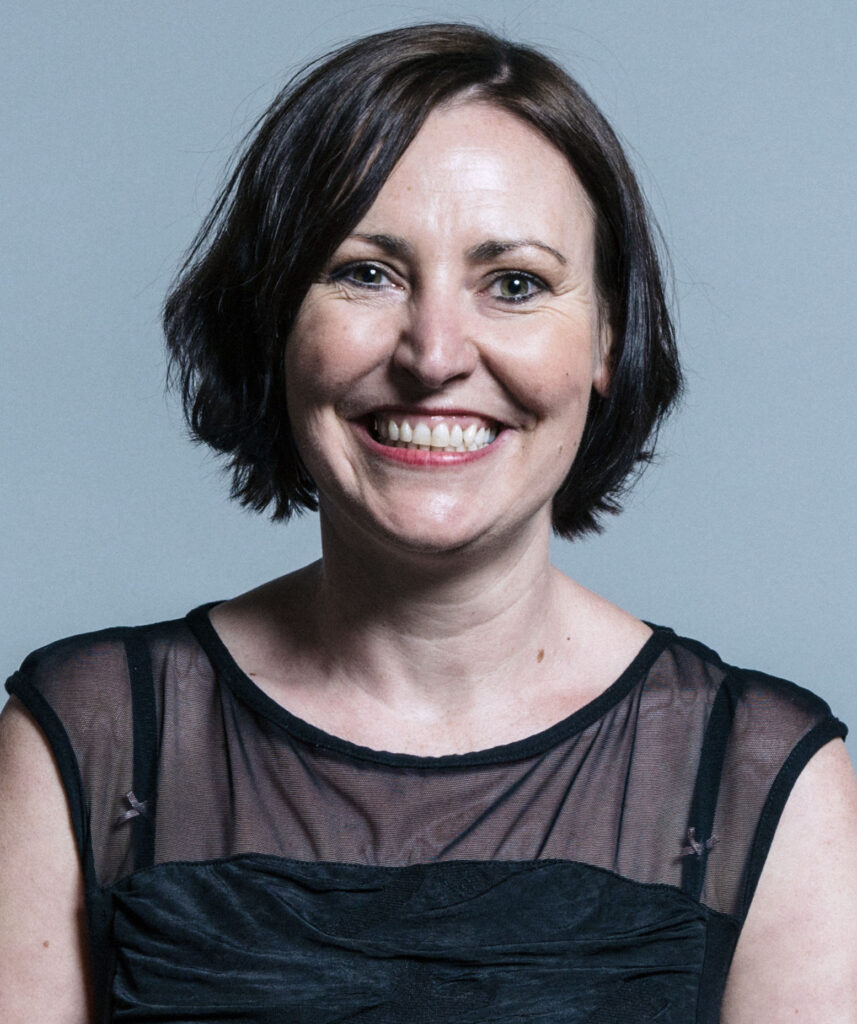 Portrait photo of Vicky Foxcroft MP, facing the camera and smiling broadly. She is wearing a sleeveless black top.
